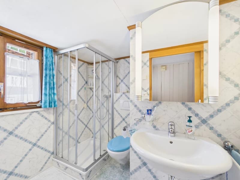 Bathroom with shower, toilet, sink, mirror, and blue curtains