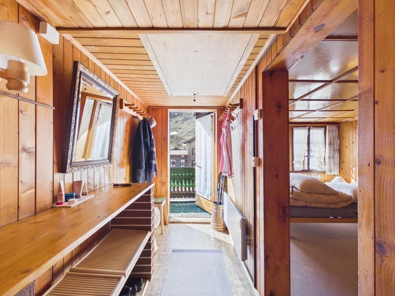 wooden walls, wooden floor, mirror, shelves, clothes hanging, balcony, bed with pillows