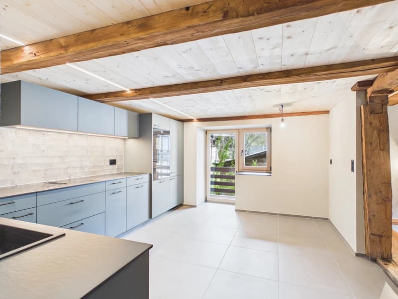 modern kitchen with wooden beams, white tiles, blue cabinets, stainless steel appliances, large window with balcony