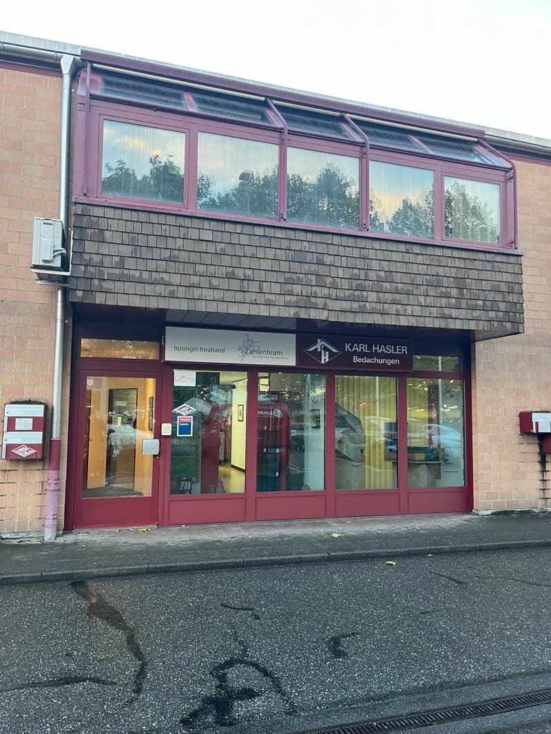 Two-story brick building with modern storefront, glass windows, and a name sign.