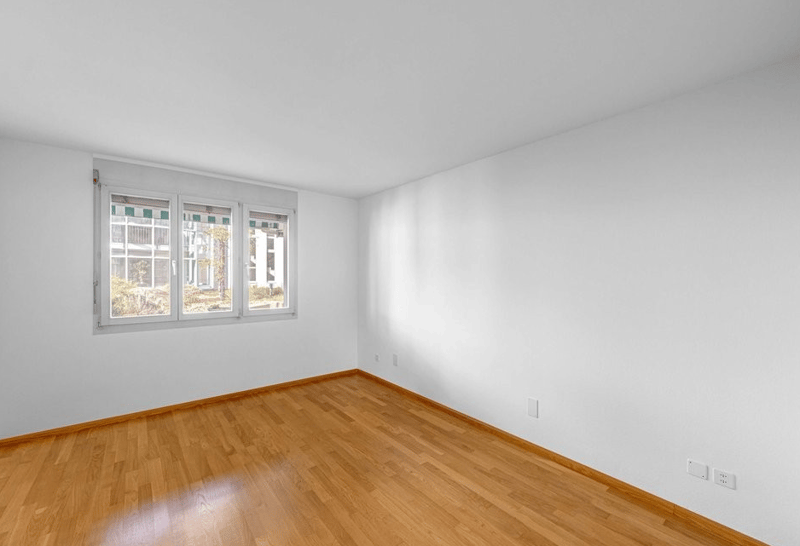 empty room, white walls, wooden floor, single window, electrical outlets