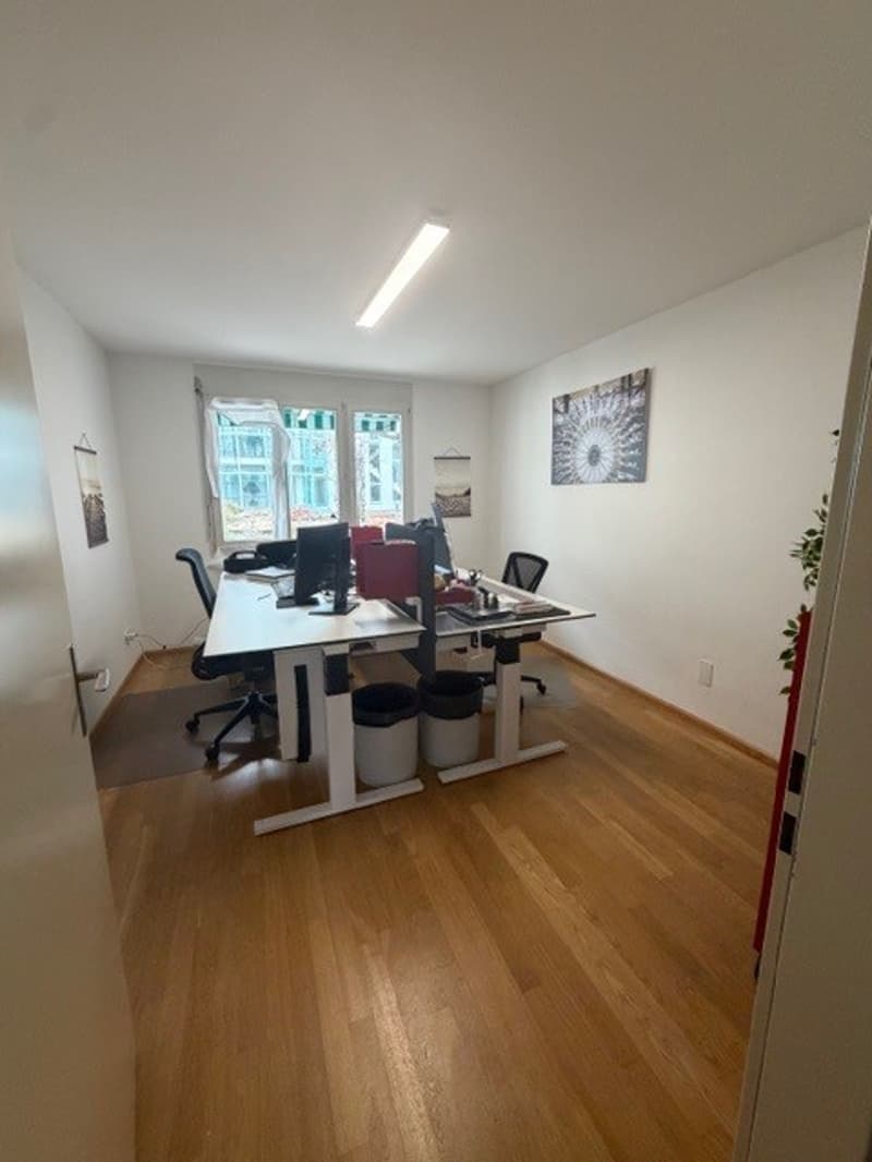 Two tables, two chairs, desk computers, desk lamps, trash cans, picture on the wall