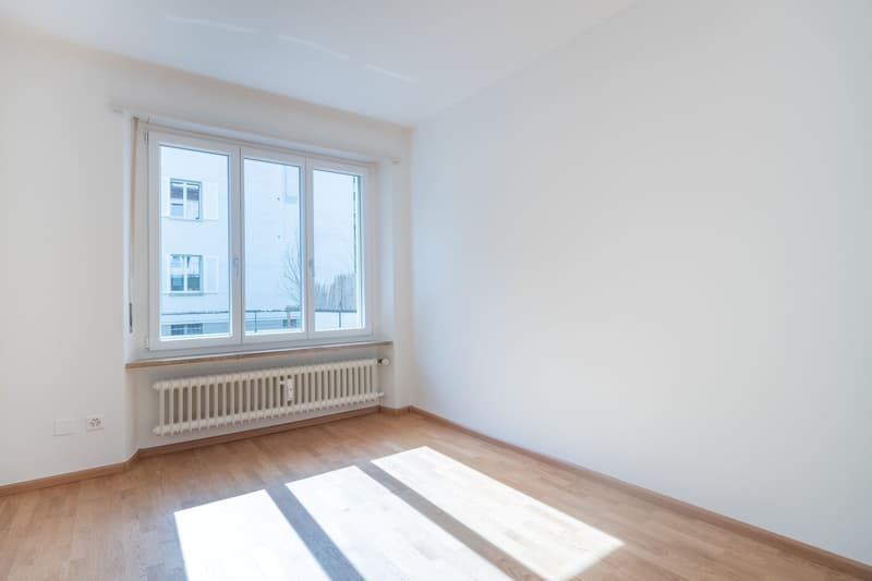 empty room with windows, white walls, wooden floor, radiators