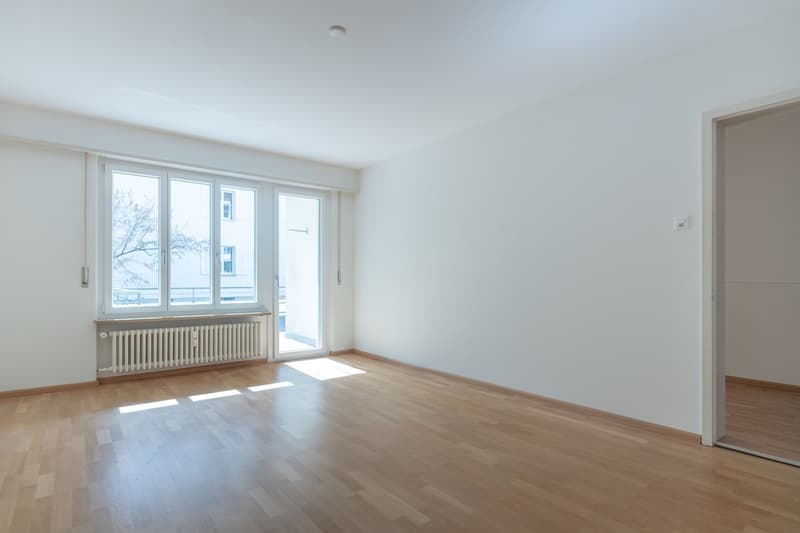 empty room with windows, wooden floor, white walls, central heating