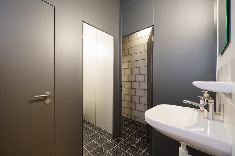 Bathroom with white sink, faucet, soap dispenser, and tiled floor.