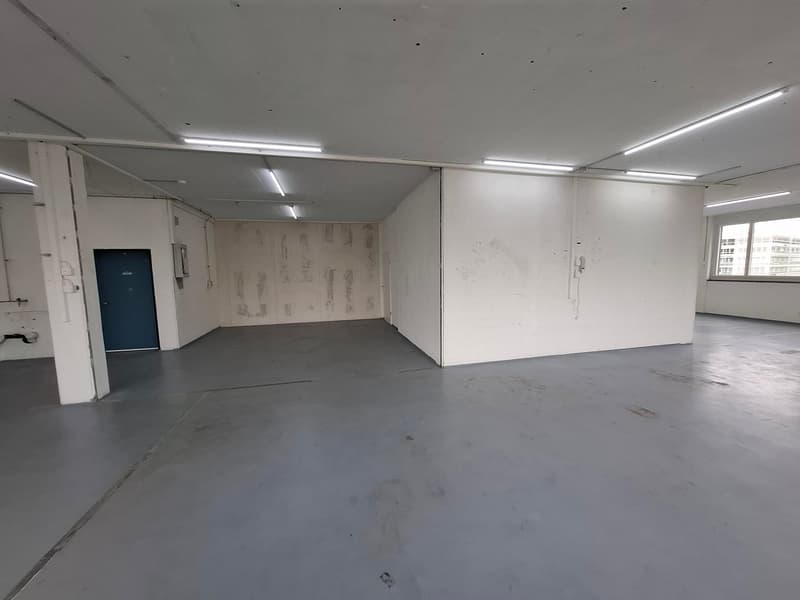 Empty room, concrete floor, white walls, windows, lighting fixtures, door