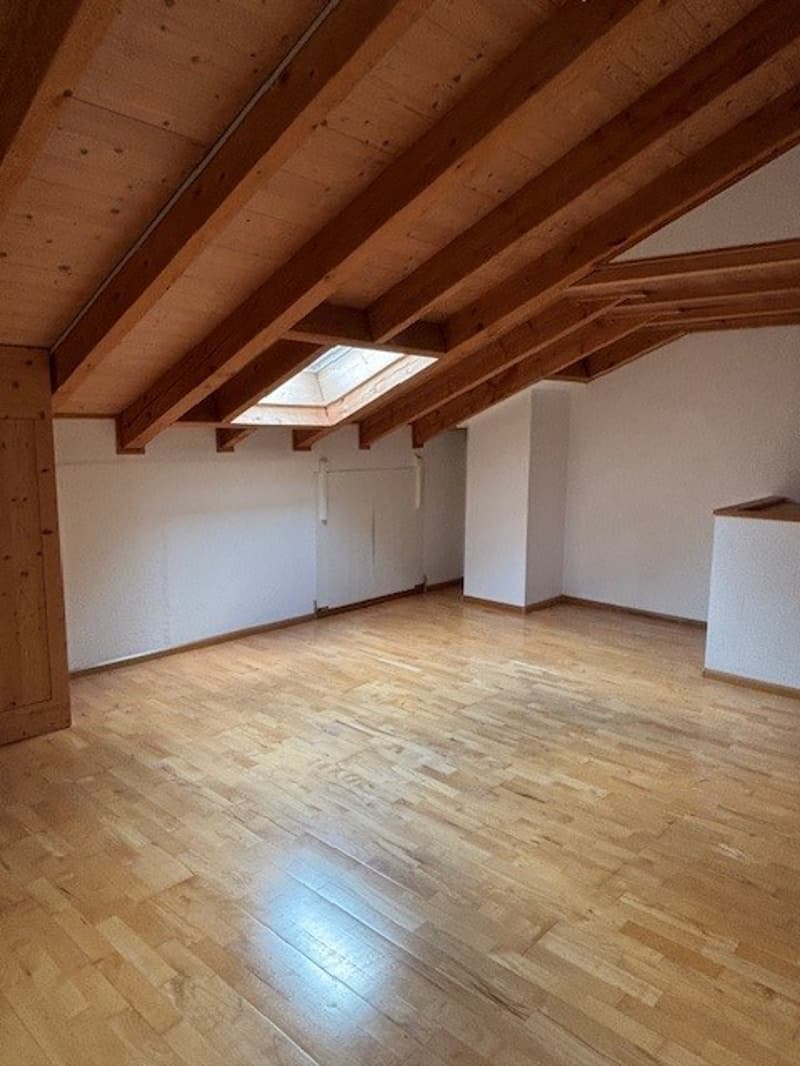 Wooden exposed beams, wooden floor, skylight window, empty room, white walls, door