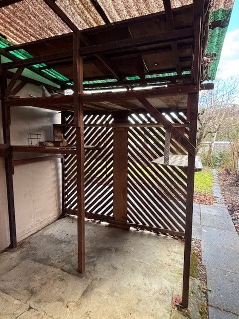 wooden structure, multiple shelves, white walls, concrete floor, green metal roof