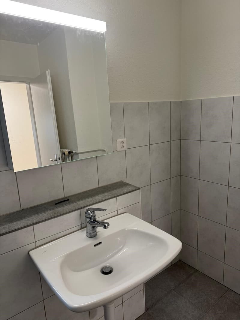 Bathroom with white sink, mirror, and tiled walls