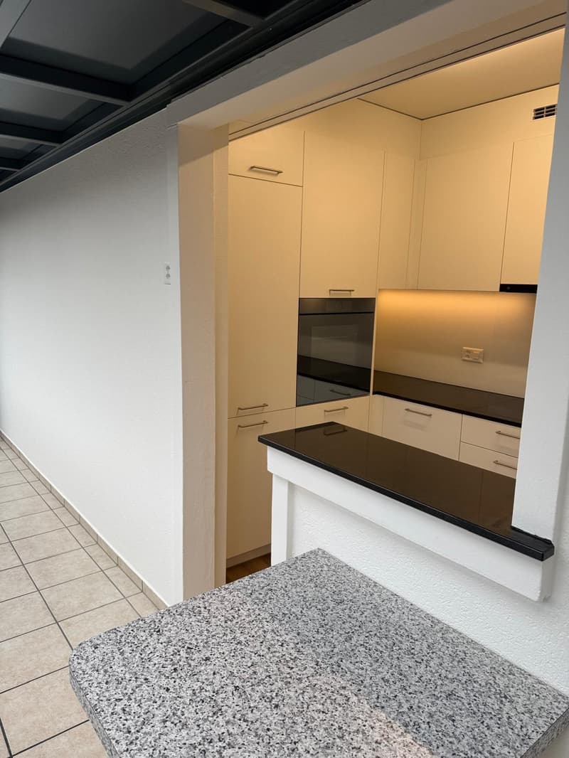 modern kitchen with white cabinets, black countertops, granite island, built-in oven, dishwasher, washing machine