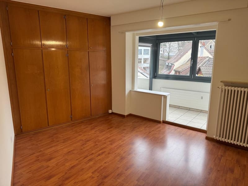 empty room, wooden floor, large wooden cabinets, window with balcony, radiator