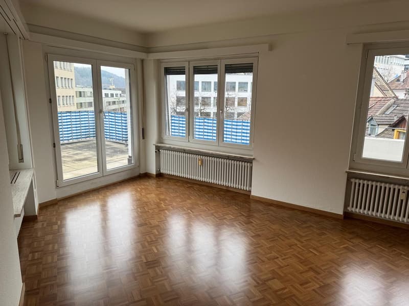 empty room, wooden floor, large windows, balcony, radiators, white walls