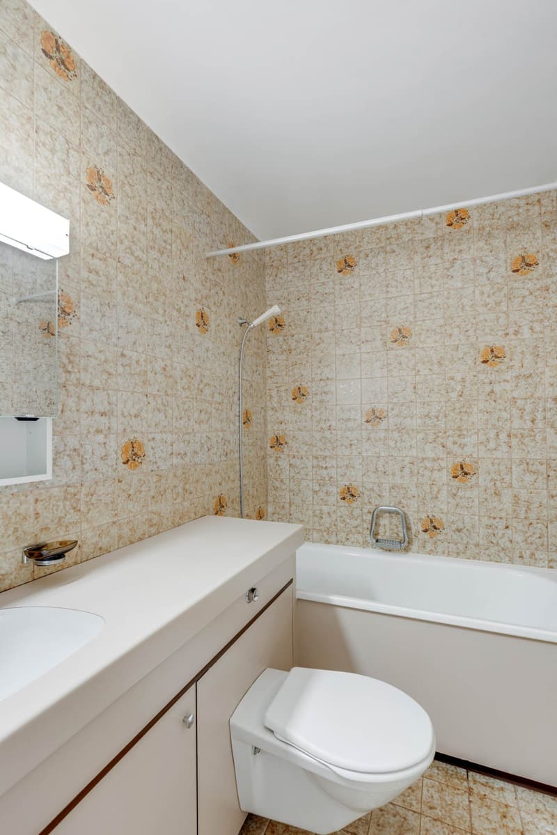 Bathroom with white bathtub, toilet, sink, showerhead, white tiled walls and floor