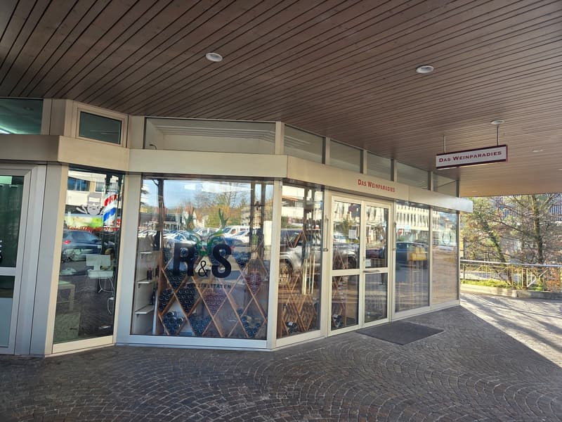 A building entrance with large glass walls, glass doors, and a wooden ceiling