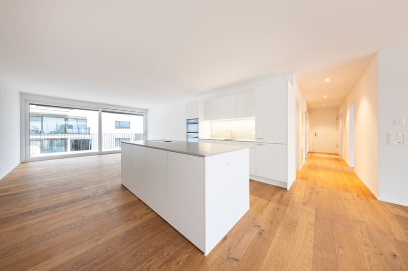 Kitchen area with white cabinets, grey countertop, balcony with large windows
