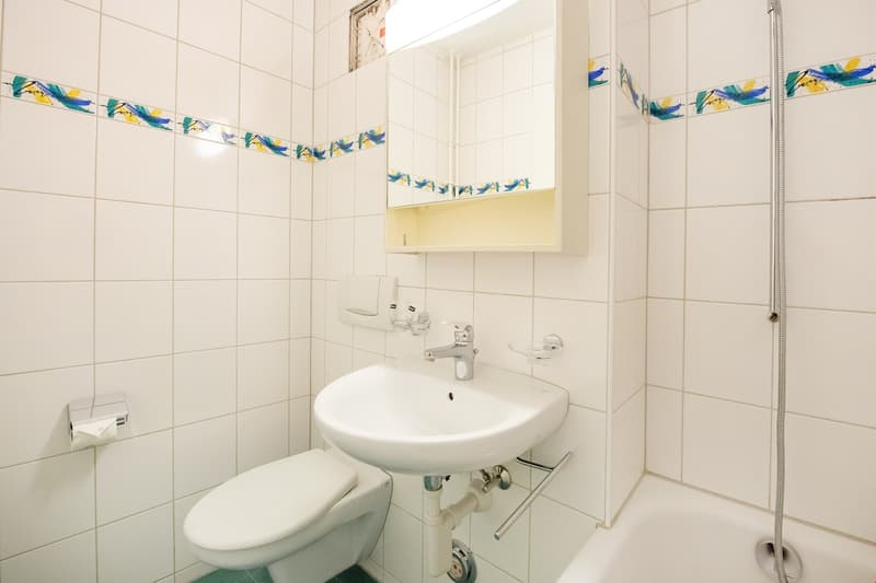 modern bathroom, white tiled walls, white sink, white toilet, mirror with medicine cabinet, shower