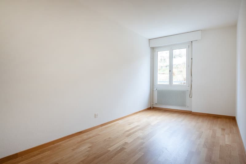 empty room with hardwood floors, white walls, window, and white radiator