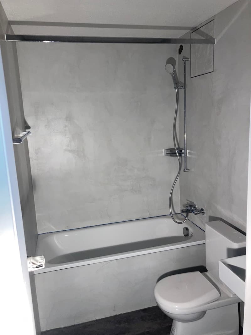 Bathtub and toilet in the room, shower head is on the wall
