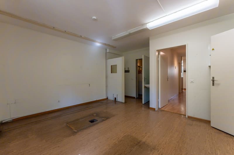 Empty room with wooden floor, white walls, two doors, a hole on the floor