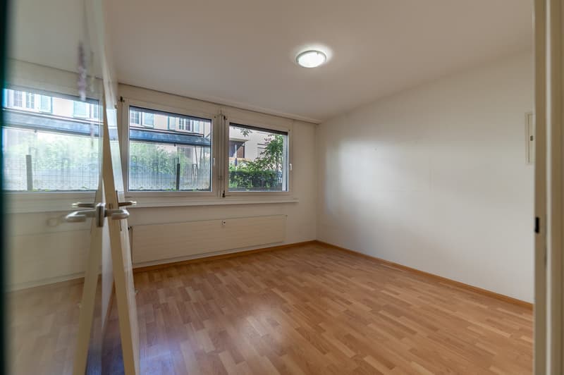 Empty room, wooden floor, glass doors, two large windows, white walls, ceiling light, radiator
