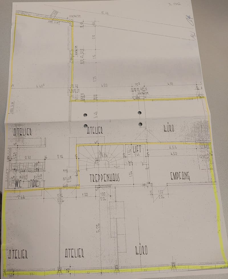 A detailed architectural floor plan with various sections labeled, including 'Atelier', 'Treppenhaus', and 'Empfang'. Dimensions and specific design elements are indicated, along with a lift/elevator marked on the plan.
