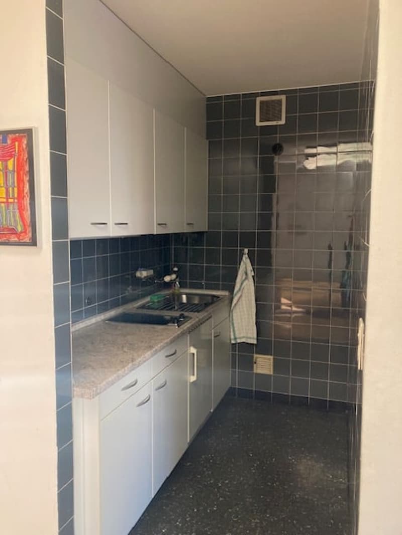 Kitchen with white cabinets, granite countertop, double sink, and black tiles