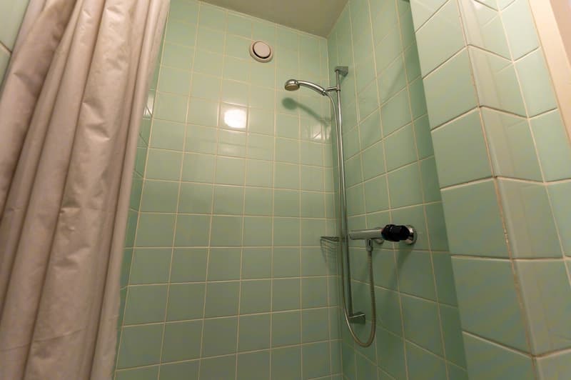 shower area with shower head, shower curtain, tiled walls