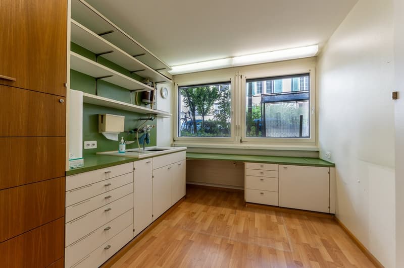Laundry room with wooden cabinets, green countertops, white drawers, sink, shelves, and a window
