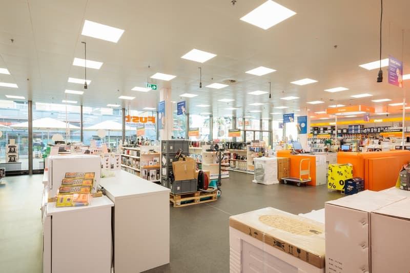 Large retail store with various household appliances, electronics, and other products displayed on shelves and racks. The store has bright lighting and a spacious layout.