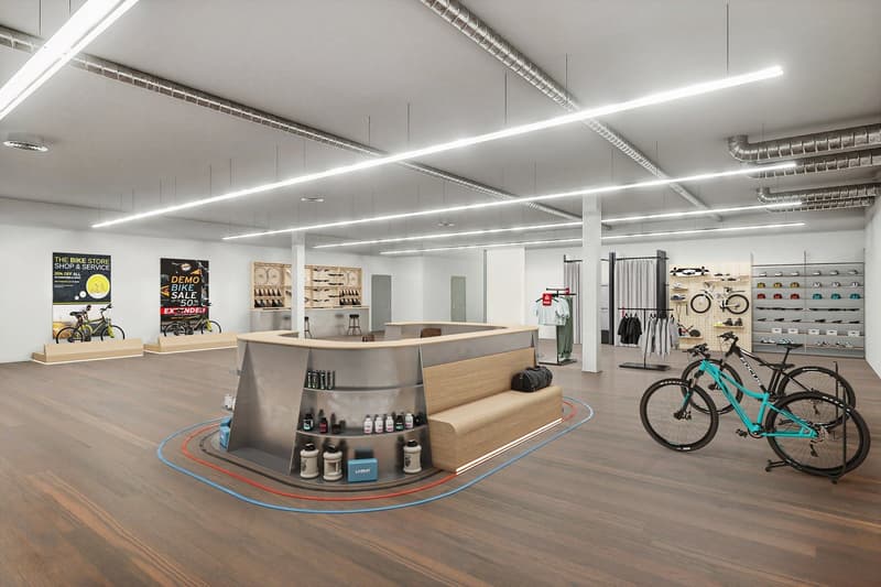 modern interior design with white walls, grey flooring, large windows, bike display with bikes and helmets, counter with shelves, racks with bicycles and shoes, blue lines on the floor