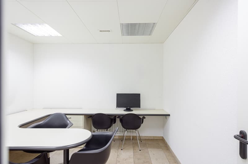 small meeting room, office furniture, 4 black chairs, round table, computer monitor, white walls, beige floor