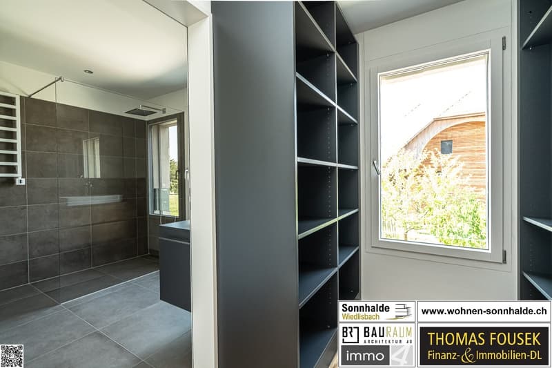 bathroom with shower and storage cabinet, walk-in closet with shelving