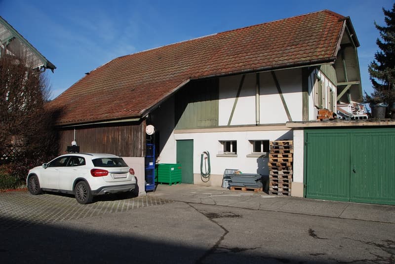 Red roof, two garages, white walls, green doors, car parked