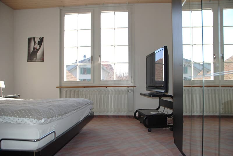 single bed, tv on a tv stand, white walls, radiators, small lamp, picture on wall
