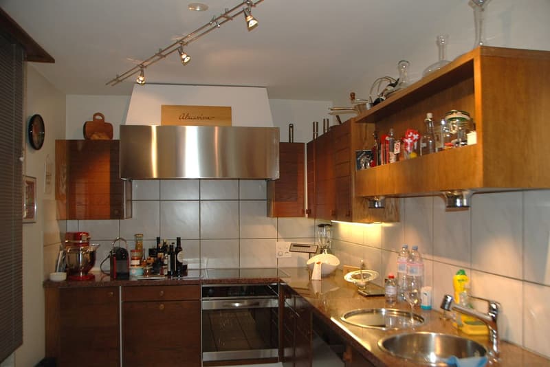 Wooden cabinets, granite countertop, stainless steel appliances, open shelving, tiled backsplash