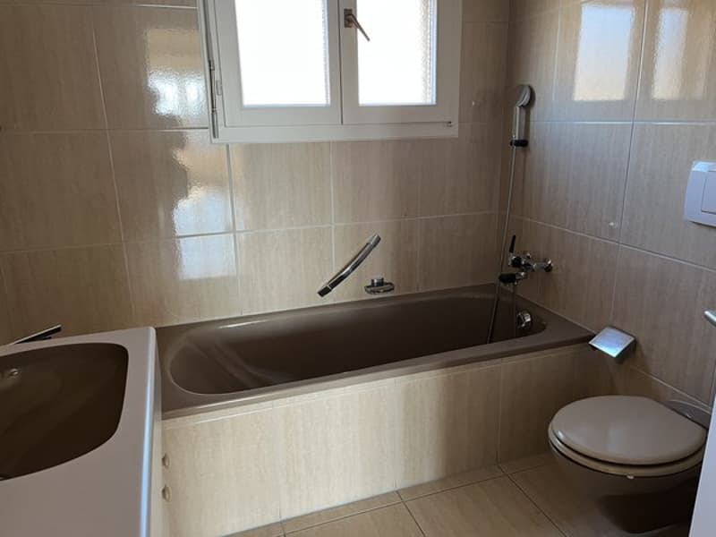 Bathroom with a bathtub, toilet, and tiled walls