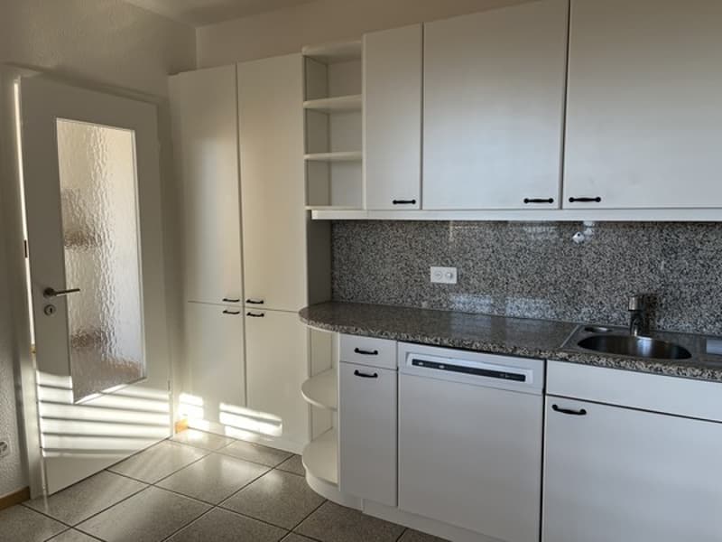 Spacious kitchen with white cabinets, granite countertops, and a dishwasher. The kitchen has a modern and clean design.