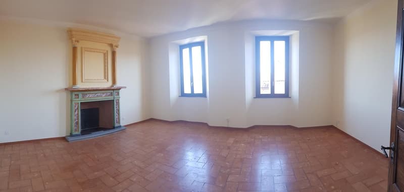 Spacious living room with high ceilings, large windows, hardwood floors, and a decorative fireplace with a colorful mantel.