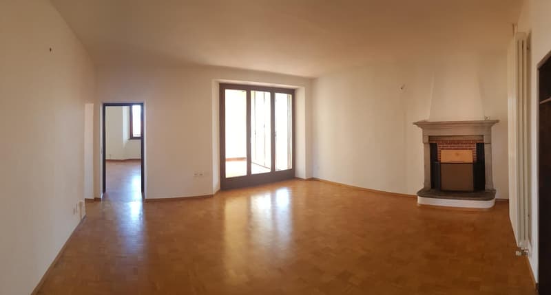Spacious living room with hardwood floors, large windows, and a brick fireplace