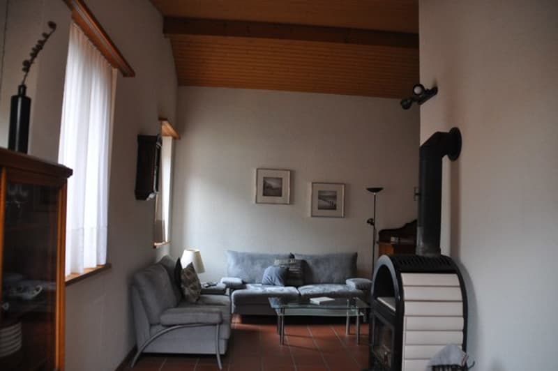 a fireplace, gray couch, coffee table, wall pictures, lamps