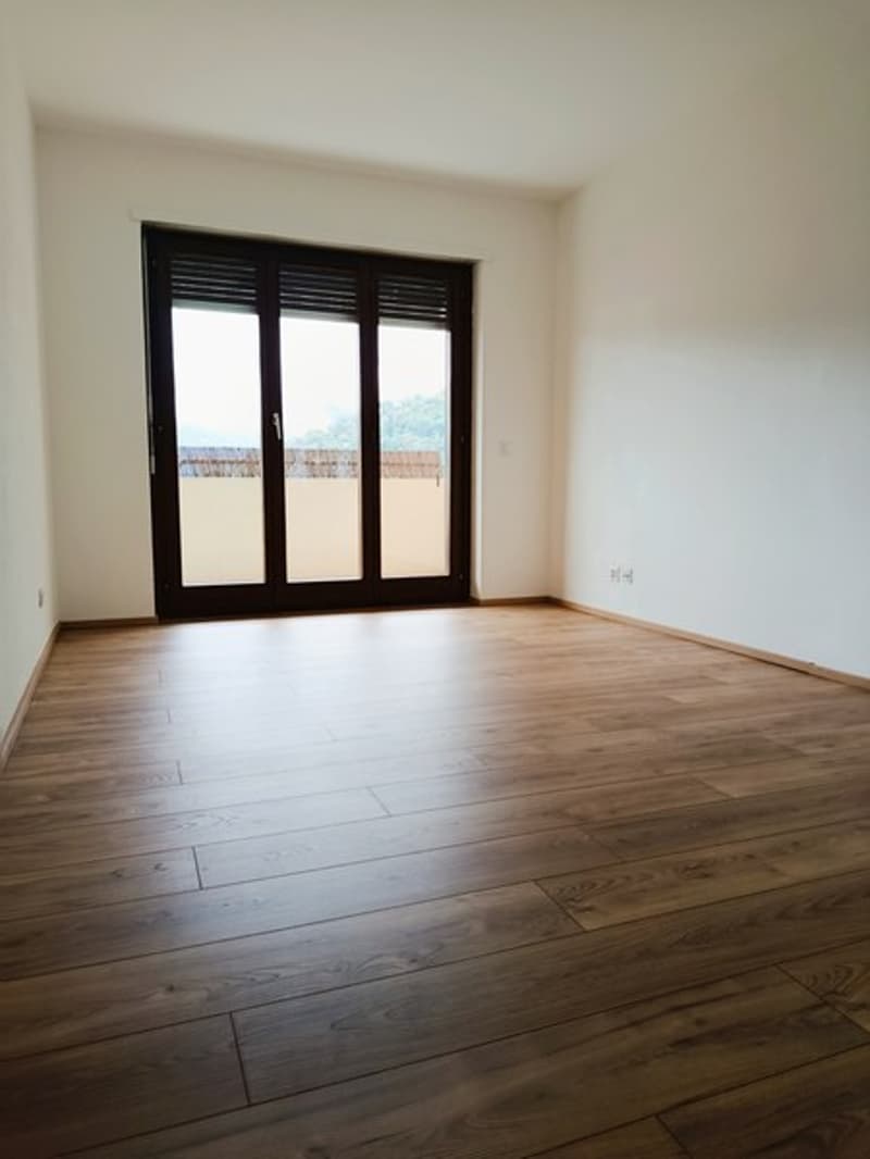 empty room, wooden floor, white walls, sliding glass doors leading to a balcony