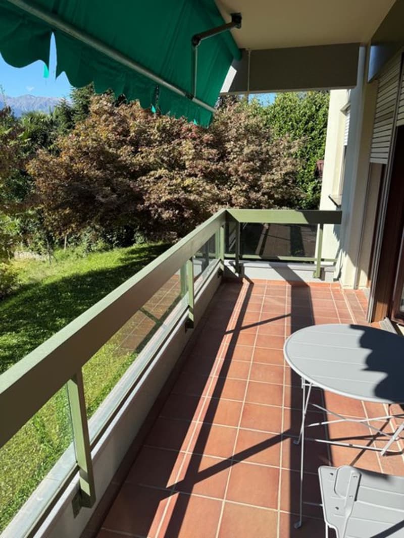 Terrace, metal table, white chairs, green canopy, tile flooring, fenced railings
