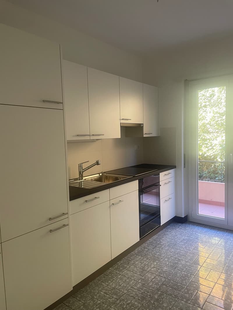 white cabinets, black countertop, stainless steel sink, faucet, oven, balcony