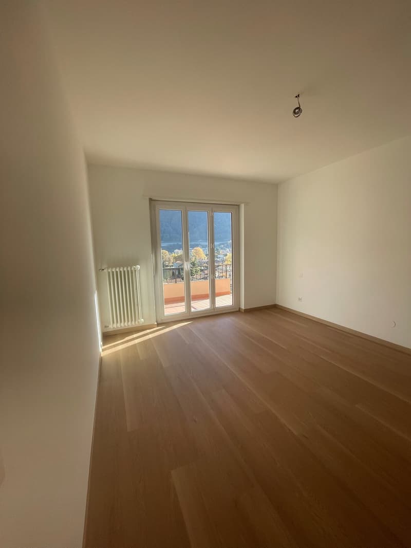 empty room, wooden floor, white walls, sliding glass door leading to balcony, white radiator
