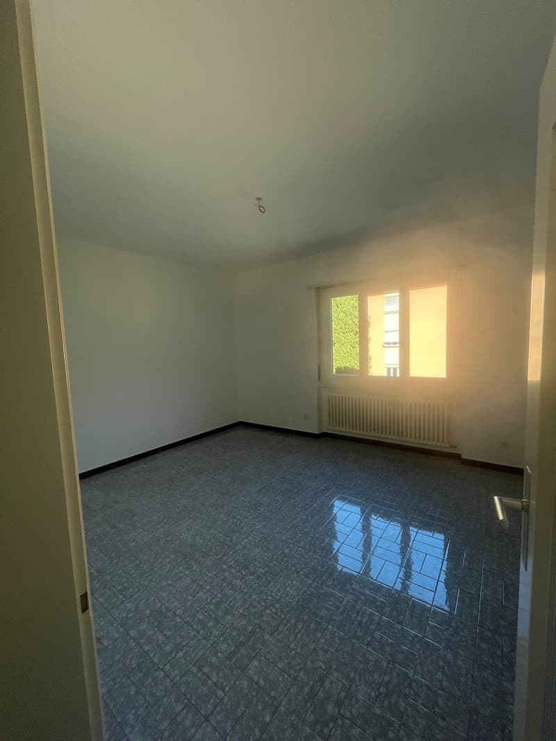 Empty room, tiled floor, white walls, window with view, radiator