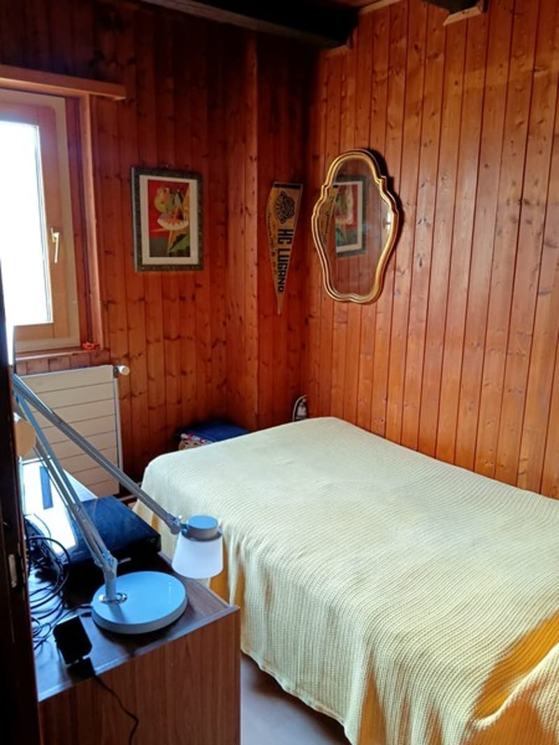 Single bed, wooden desk, lamp, radiator, window, mirrors, pictures on the wall