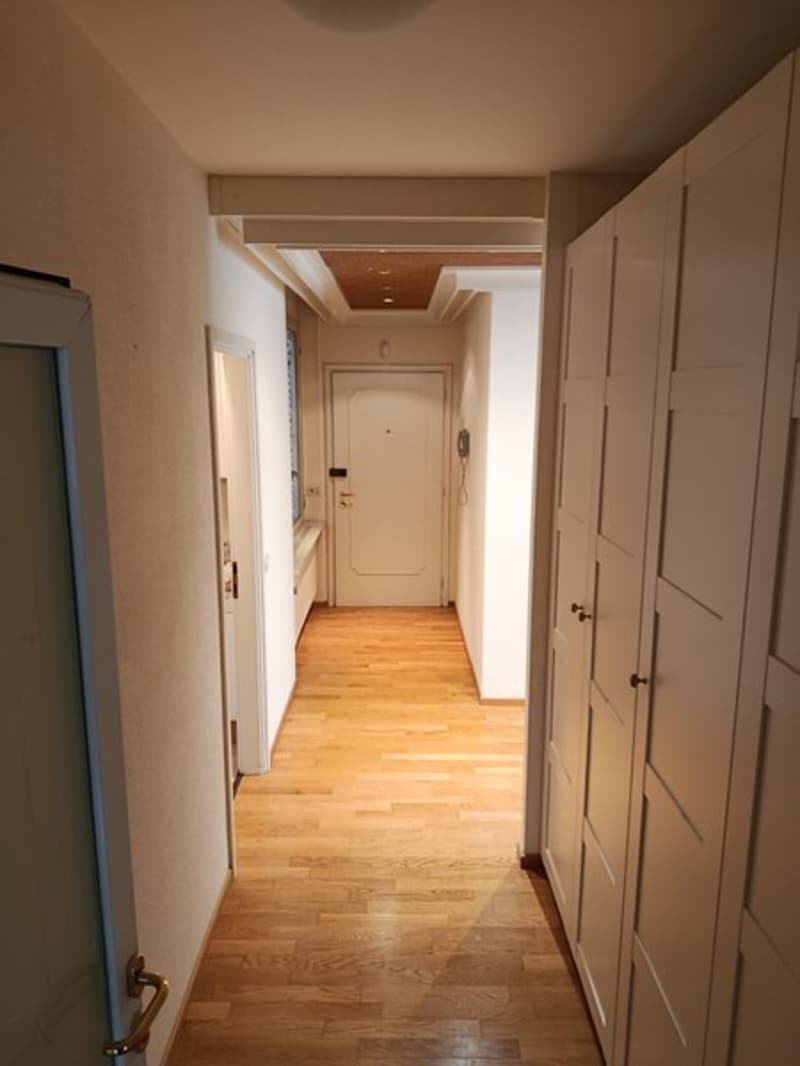 empty hallway, wooden floor, white walls, two sets of tall white cupboards