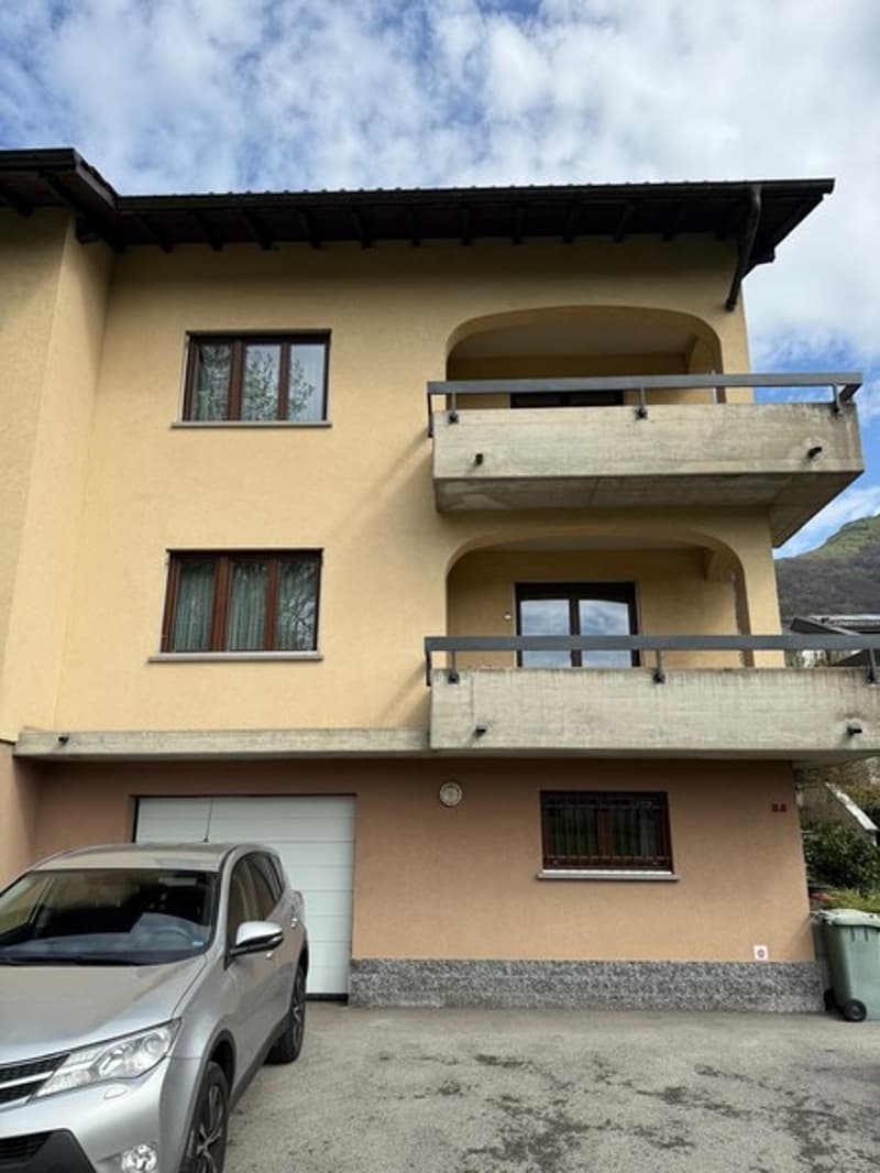 3 story house, beige exterior, 3 balconies, garage, car parked in front