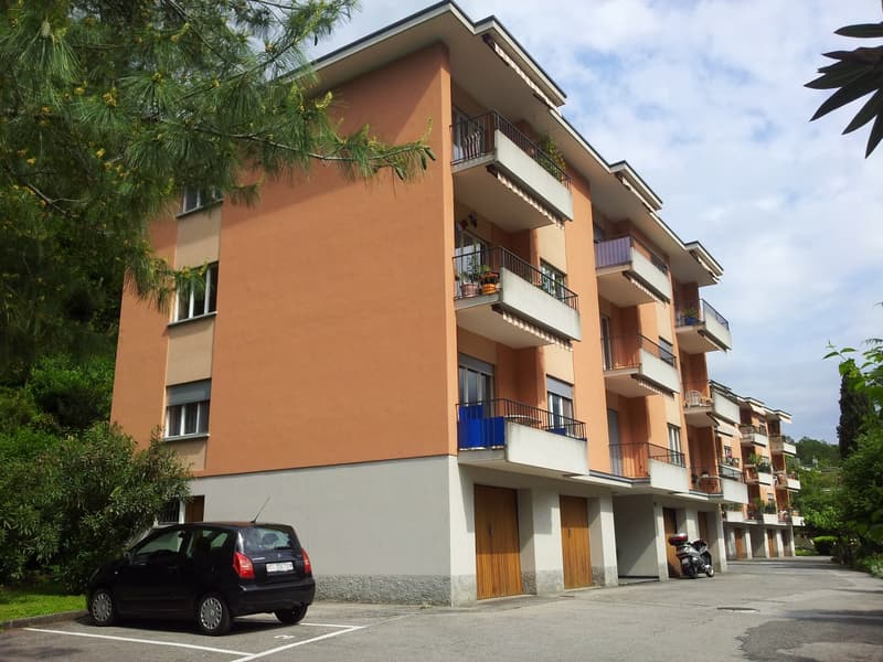 4 story building, orange and white walls, balconies, parking lot, car parked