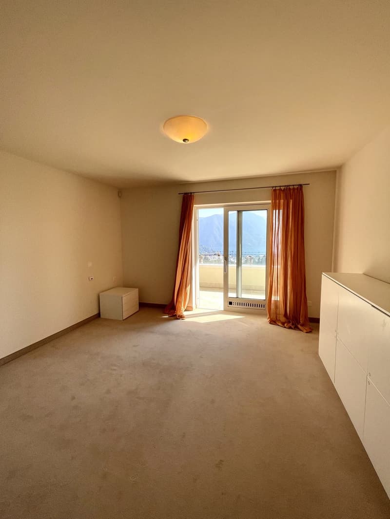Empty room with beige walls, beige carpet, white ceiling, sliding glass door, and a small white cabinet.